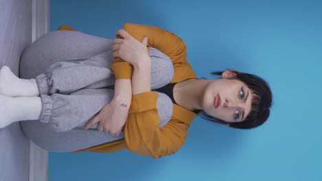 Vertical-video-of-Depressed-young-woman.-It-sits-by-the-wall.